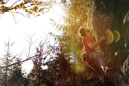 Young man climbing at a rock face on a sunny day, Schwaerzer Wand, Bavaria, Germany