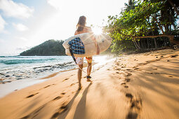 Young female surfer walking along the beach, Sao Tome, Sao Tome and Principe, Africa