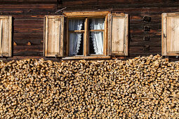 old traditional timber house, firewood stacked below windows with wooden shutters, Bregenzerwald, Vorarlberg, Austria