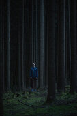 Young male runner standing in the forest and looking up, Allgaeu, Bavaria, Germany