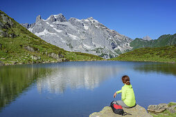 Frau beim Wandern sitzt an Bergsee, Drei Türme und Drusenfluh im Hintergrund, Rätikon, Vorarlberg, Österreich