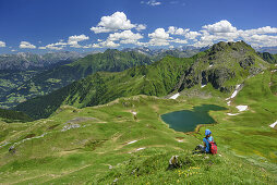 Woman sitting in meadow and looking towards lake Tilisunasee and Tilisuna-Seehorn, Raetikon, Vorarlberg, Austria