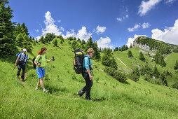 Three persons hiking through meadow, Hennenkopf, Ammergau Alps, Upper Bavaria, Bavaria, Germany