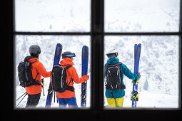 Drei junge Skifahrer stehen außerhalb einer Hütte in den Bergen, Andermatt, Uri, Schweiz