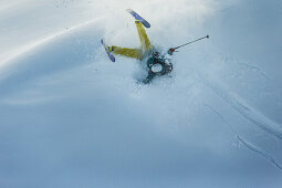 Young male skier falling into the deep powder snow apart the slopes, Andermatt, Uri, Switzerland