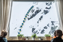 Guests looking through a window at a male skier jumping down a cliff, Andermatt, Uri, Switzerland