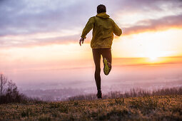 Young man running over a meadow during sunset, Allgaeu, Bavaria, Germany