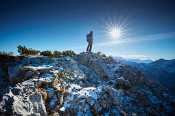 Hiker in the late Autumn at the summit of the Scheinbergspitze, Ammergauer Alps, Germany