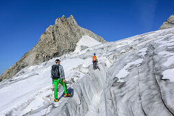 Mann und Frau steigen über spaltigen Gletscher auf, Kuchelmooskopf im Hintergrund, Kuchelmoosferner, Zillergrund, Reichenspitzgruppe, Zillertaler Alpen, Tirol, Österreich