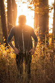 Young male runner standing in a forest on a wonderful autumn day, Allgaeu, Bavaria, Germany