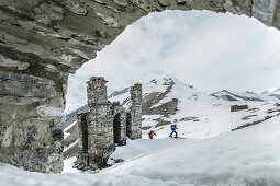 Two skiers hiking apart a ruin in the mountains, Gudauri, Mtskheta-Mtianeti, Georgia
