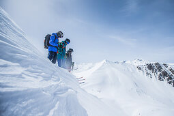 Drei junge Skifahrer stehen auf der Kante einer Schneewehe in den Bergen, Gudauri, Mzcheta-Mtianeti, Georgien