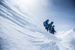 Drei junge Skifahrer stehen auf der Kante einer Schneewehe in den Bergen, Gudauri, Mzcheta-Mtianeti, Georgien