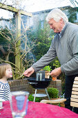 Granddaughter und grandfather blowing matches, Hamburg, Germany