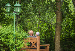 Father and two children sitting on a bench in the garden, Holiday, Vacation, Summer, Spreewald, Oberspreewald, Brandenburg, Germany