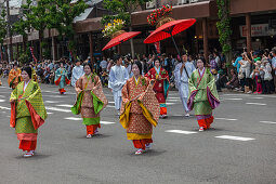 Women in traditional dress with big red umbrella during Festival Aoi Matsuri in Kyoto, Japan