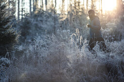 Young man running through a frost covered forest, Allgaeu, Bavaria, Germany