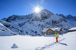 Woman backcountry skiing ascending towards Breiter Grieskogel, hut Winnebachseehuette in background, Breiter Grieskogel, Stubai Alps, Tyrol, Austria