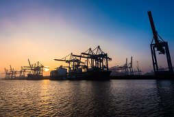 Sonnenaufgang an einem Wintertag im Hamburger Hafen am Containerterminal Burchardkai von der Elbfähre aus gesehen, Hamburg, Deutschland