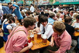 Young people in traditional cloth with beer mugs to toast at Oktoberfest, Munich, Bavaria, Germany