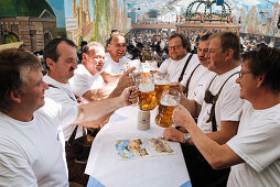 Männer mittleren Alters stossen mit Bierkrügen an, Oktoberfest, München, Oberbayern, Bayern, Deutschland