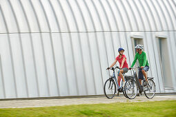 Man and woman on eBikes, City, Munich, Bavaria, Germany