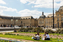 Place de la Bourse mit jungen Menschen die im Gras sitzen, Bordeaux, Gironde, Nouvelle-Aquitaine, Frankreich, Europa