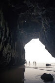 Five young men walking through a cave at the beach Praia da Amoreira,  Aljezur, Faro, Portugal
