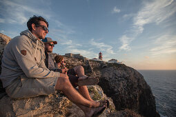 Four young men enjoying the sunset on a cliff at the beach Praia da Amoreira,  Aljezur, Faro, Portugal