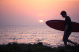 Junger Surfer läuft mit seinem Brett am Strand von Praia da Amoreira,  Aljezur, Faro, Portugal