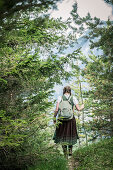 Junge Frau in Tracht wandert durch die Wälder auf dem Falkenstein, Pfronten, Bayern, Deutschland