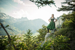 Junge Frau in Tracht steht auf einem Felsen auf dem Falkenstein im Allgäu, Pfronten, Bayern, Deutschland