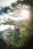 Young woman in traditional costume hiking through the forests on the Falkenstein, Pfronten, Bavaria, Germany