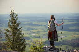 Junge Frau in Tracht genießt den Ausblick über das Allgäu auf dem Falkenstein,  Pfronten, Bayern, Deutschland