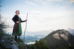 Young woman in traditional costume standing on a rock on the Falkenstein in the Allgaeu, Pfronten, Bavaria, Germany