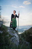 Junge Frau in Tracht steht auf einem Felsen auf dem Falkenstein im Allgäu, Pfronten, Bayern, Deutschland