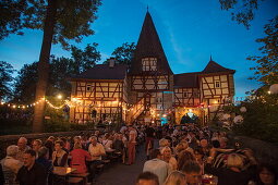 Menschen genießen Frankenwein beim Weinfest am Rödelseer Tor in der Abenddämmerung, Iphofen, Fränkisches Weinland, Franken, Bayern, Deutschland, Europa