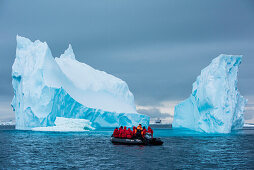 Ein Zodiac Schlauchboot und das Expeditions- Kreuzfahrtschiff MS Bremen (Hapag-Lloyd Cruises) werden von einem turmhohen Eisberg überragt, Active Sound, Antarktis