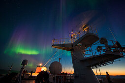 Die Nordlichter (auch Polarlichter oder Aurora Borealis) erhellen den Himmel kurz nach Sonnenuntergang, gesehen von an Bord Expeditions-Kreuzfahrtschiff MS Bremen (Hapag-Lloyd Cruises), zwischen Nordostkap und Kap Ossory, Nunavut, Nordkanada, Nordamerika