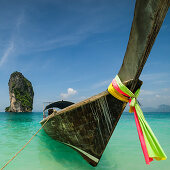 traditional colorful  cloths on a longtailboat and view to the huge rock in front of Poda beach, Andaman sea, Krabi, Thailand