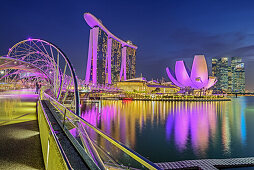 Illuminated skyline of Singapore with Helixbridge, Marina Bay Sands and ArtScience Museum reflecting in Marina Bay, Singapore