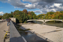 Man looking towards the gravel banks at Muffathalle, in the background you can see the Kabelsteg and behind the autumn trees the Maximilianaeum, Munich, Upper Bavaria, Germany