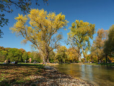 Bade- und Picknickgäste am Eisbach im herbstlichen Englischen Garten, München, Oberbayern, Deutschland