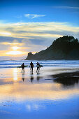 USA, Oregon, Oswald West State Park, surfers walk along the beach and out into the water at Oswald State Park, just south of Cannon Beach
