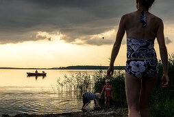 Mother with children go swimming and fishing boat on the lagoon side in Lieper Winkel, Usedom, Baltic Sea Coast, Mecklenburg-Vorpommern, Germany