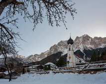 View of the snow-covered cemetery and the parish church of St. John the Baptist in front of the Großer Waxenstein, Grainau, Upper Bavaria, Germany