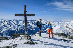 Man and woman backcountry-skiing congratulating each other on the summit, Rastkogel, Tuxer Alps, Tyrol, Austria
