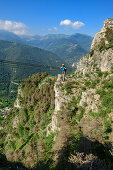 Frau am Klettersteig geht über Seilbrücke, Ferrata di Camoglieres, Val Maira, Cottische Alpen, Piemont, Italien