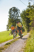 Zwei junge Männer fahren auf Gravel bikes über Feldweg, Münsing, Bayern, Deutschland