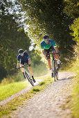 Zwei junge Männer fahren auf Gravel bikes über Feldweg, Münsing, Bayern, Deutschland